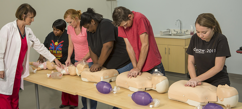 Medical Assisting students in classroom working with CPR Manikins.