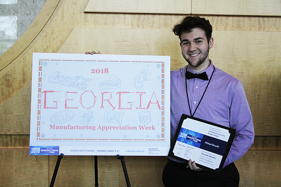 Tall male student stand next to his artwork. 