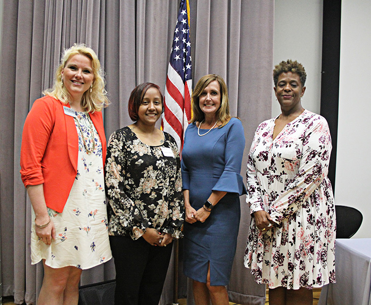 Foru females gather for a photo on a stage. 