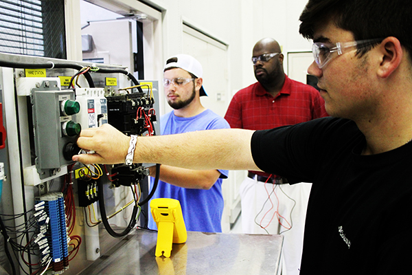 HCCA seniors and CGTC Dual Enrollment students, Dalton McNamar and Griffin Arnold, work on a project in the Industrial Systems lab at HCCA under the observation of Antonio Shelley, the program chair for CGTC. 