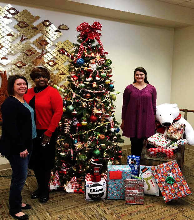 (From Left to Right) Elizabeth Eader, director of Campus Life at The Methodist Home, Ruby Holmes, project manager at CGTC, and Brittany Grier, marketing coordinator at The Methodist Home, set gifts donated by CGTC’s Institutional Effectiveness staff next to a Christmas tree at the Methodist Home for Children and Youth. 