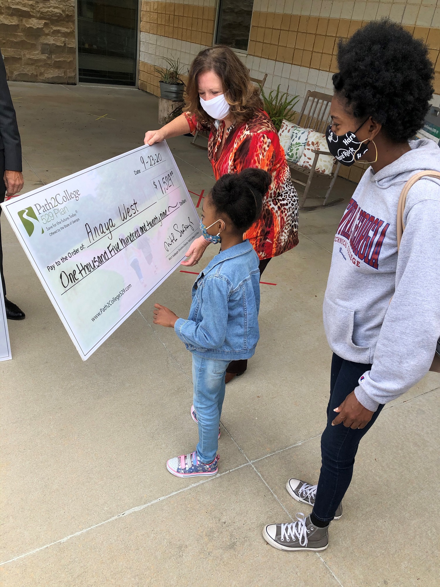  Anaya West looks at her college savings plan check alongside her mother, Adria a student in Construction Management and Center director, Linda Smith. 