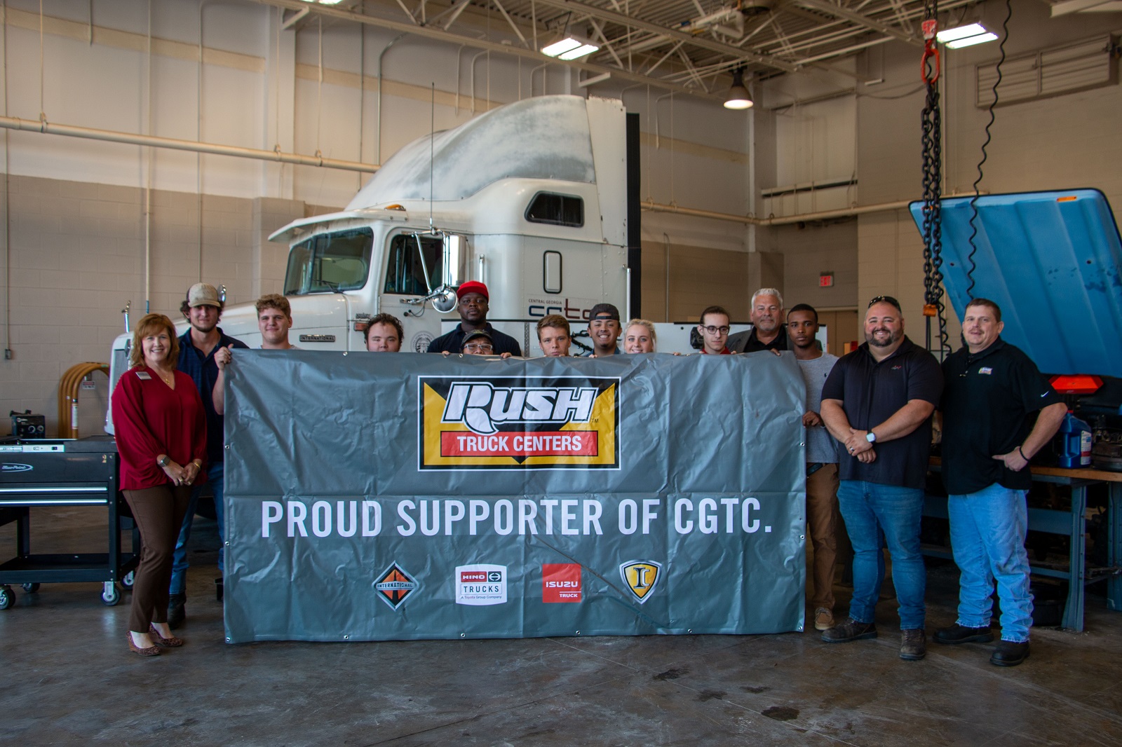 Students, faculty and staff from the Diesel Equipment Technology program and the College hold up a new banner. Rush Truck Centers of Macon recently donated new equipment to the program in September. 