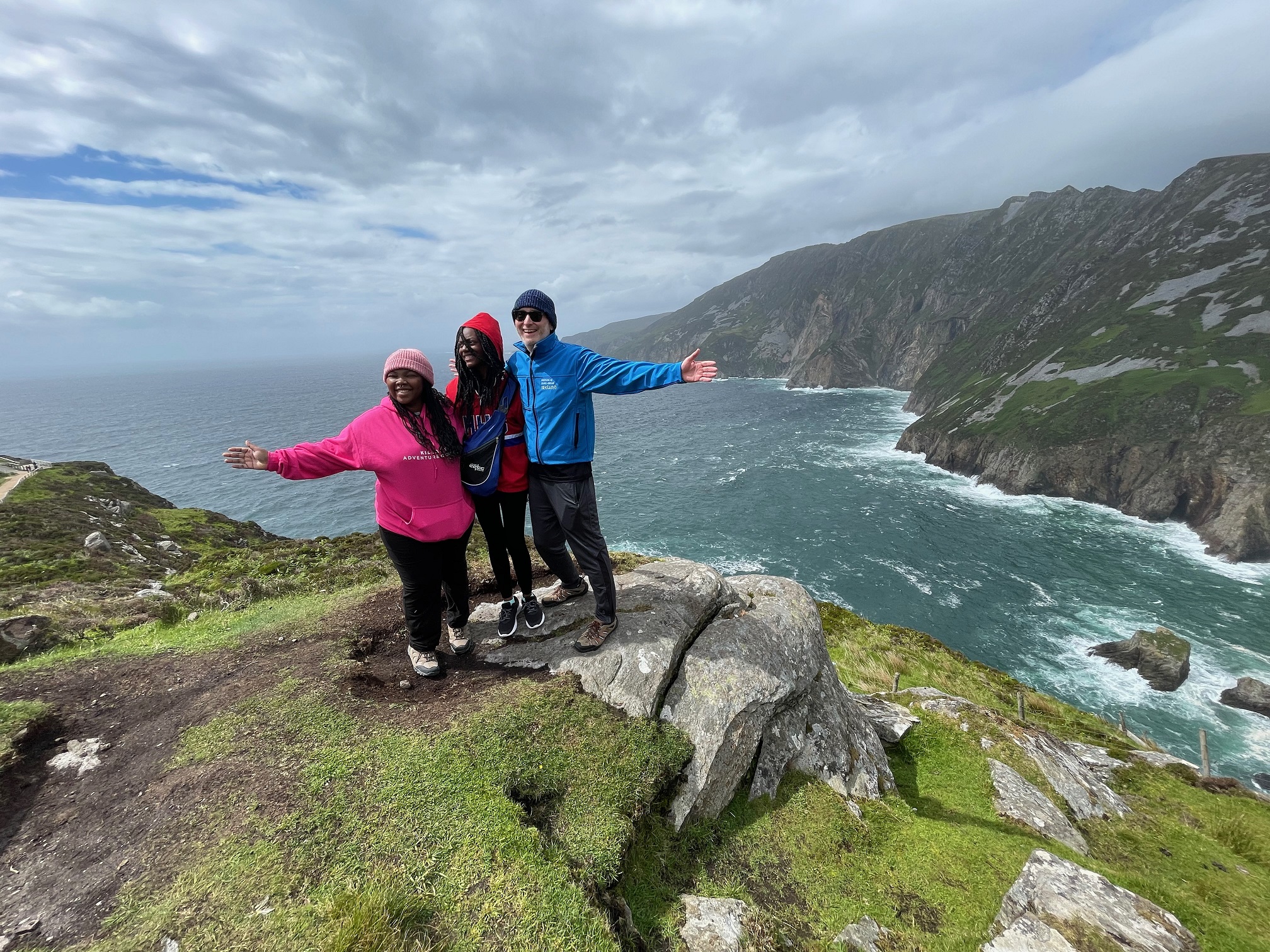 Zanobia Anderson, Brookyln Phillips and Scott Hughes, join together for a photo at the top of Sliabh Liag Cliffs in Donegal, Ireland.