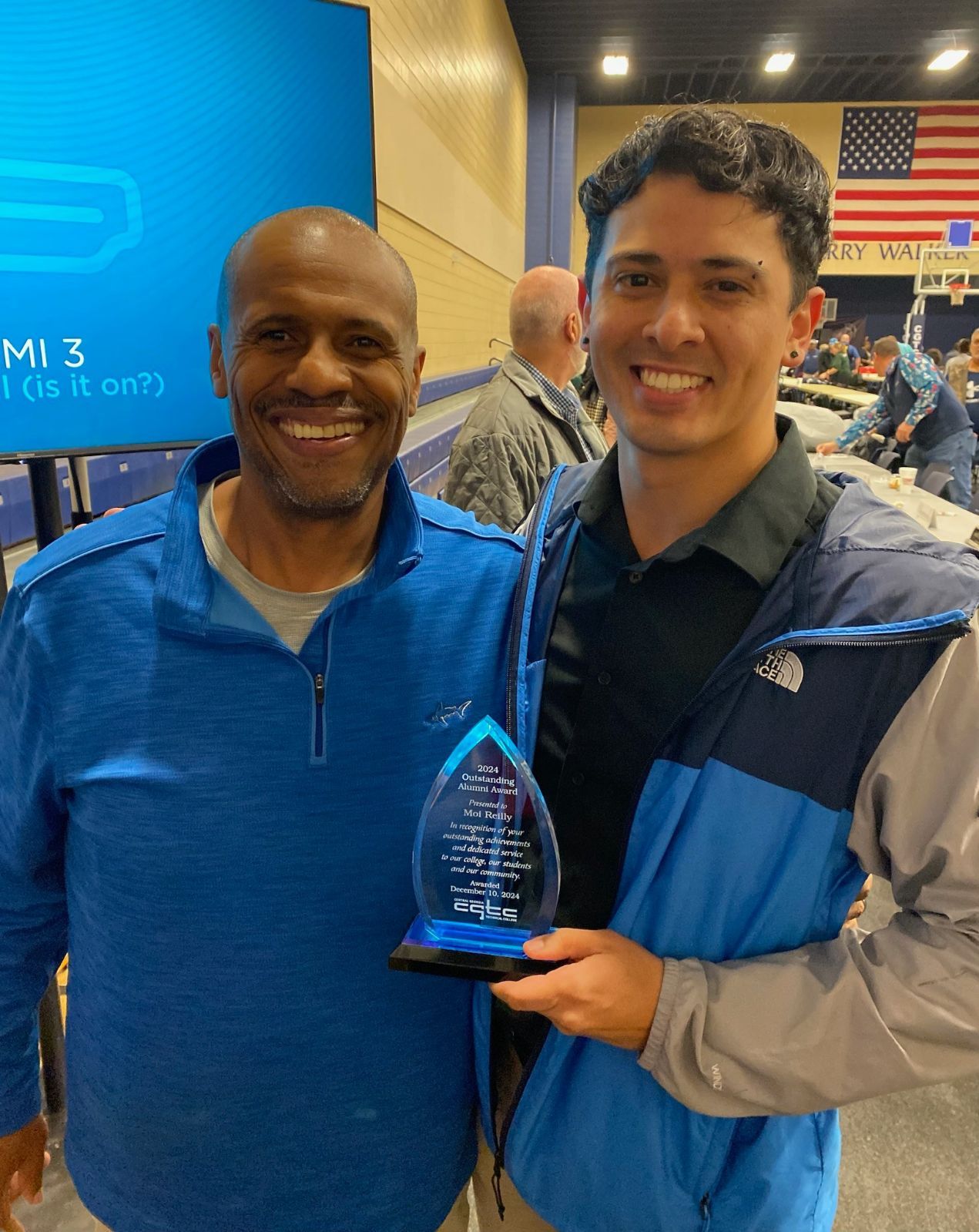Dr. Ivan Allen standing with Moi Reilly (right) proudly displays his CGTC Outstanding Alumni award .
