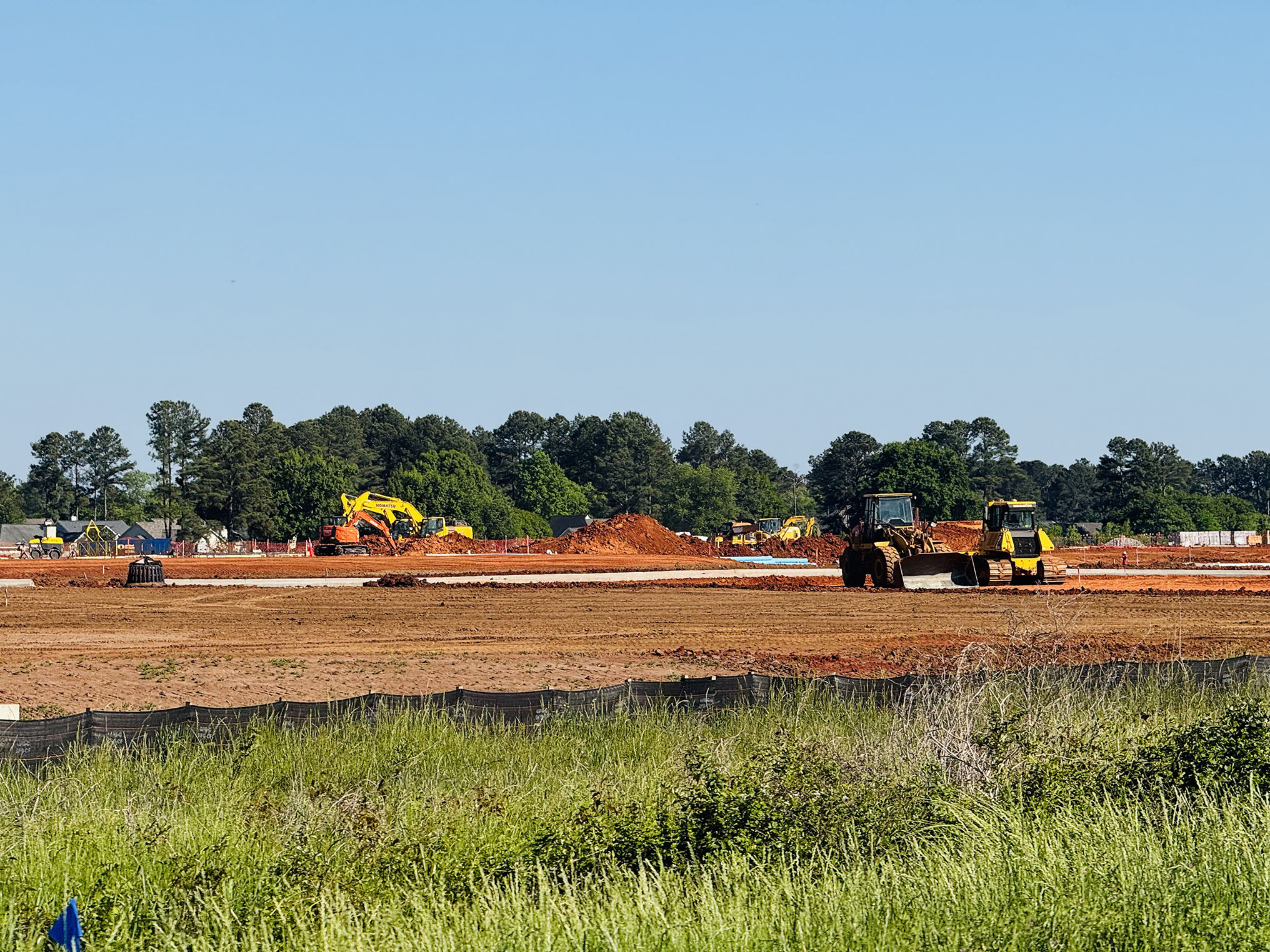 Development site full or red clay and bulldozers.