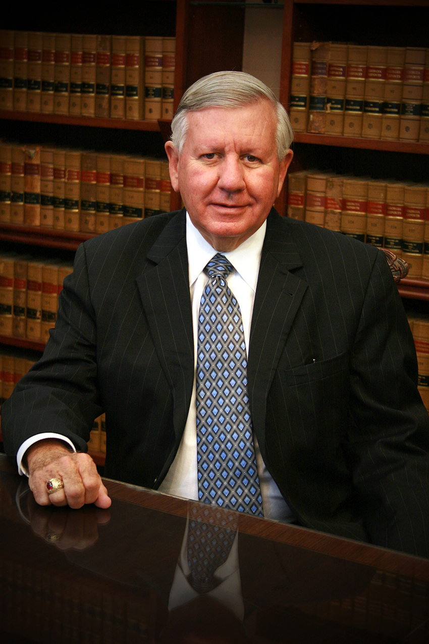 Portrait of Larry Walker in a suit sitting at a desk in a library.