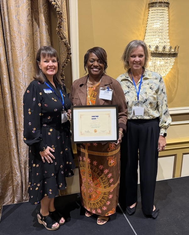 Dr. Deborah Burks holds her award, stands with two of her CGTC colleagues.