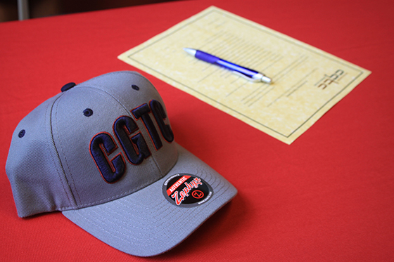 Picture is a gray, CGTC baseball cap and a document to be signed.