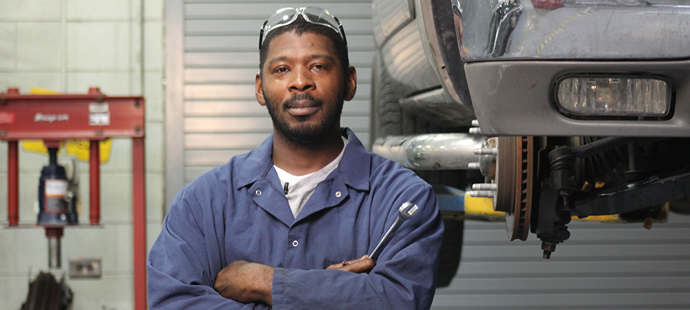 Automotive Technology student standing in front of car