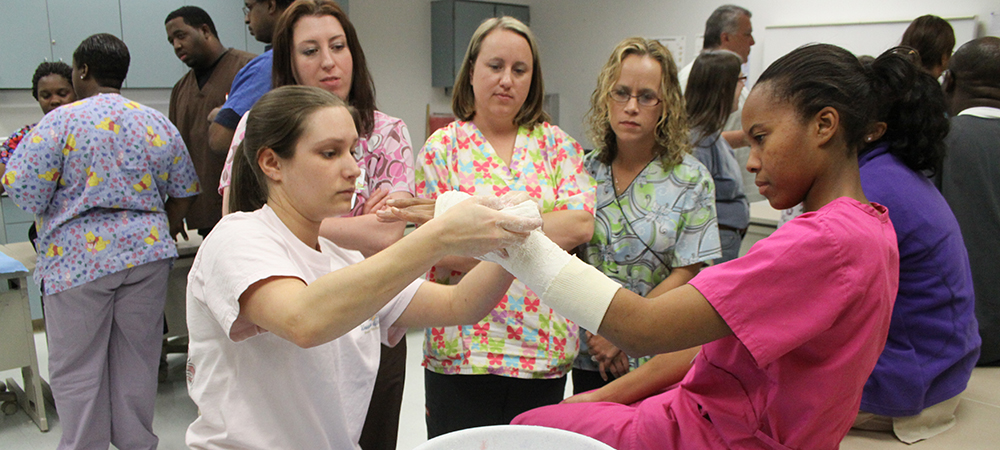 Orthopedic Technology student applying a cast to another student's arm.