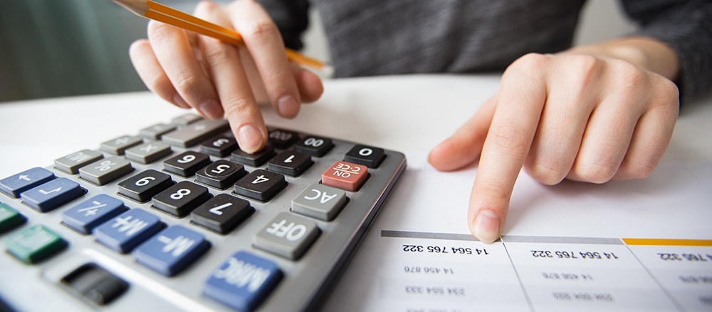 Closeup of accountant counting on calculator and working with table